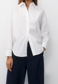 White button-up shirt with a classic collar, relaxed fit, and long sleeves, made from a smooth, lightweight fabric.