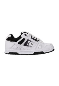 White sneaker with black accents, textured leather upper, perforated details, sturdy rubber sole, and prominent logo on the side.