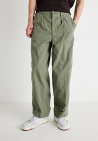 Light olive green cargo pants in durable cotton fabric, featuring two side pockets and a relaxed fit, paired with white sneakers.
