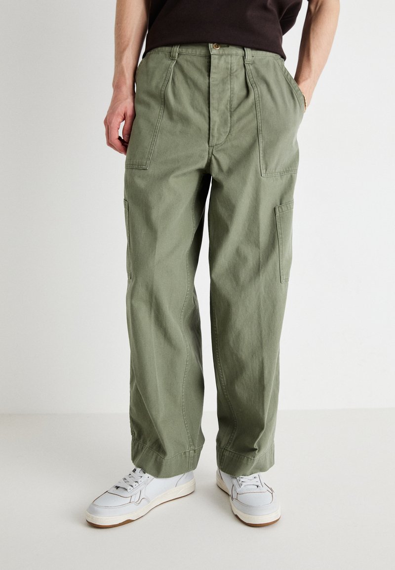 Light olive green cargo pants in durable cotton fabric, featuring two side pockets and a relaxed fit, paired with white sneakers.
