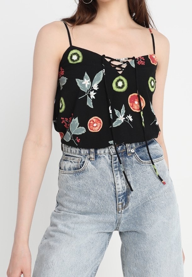 Débardeur court noir à fleurs avec bretelles spaghetti, doté d'un col à lacets et de motifs fruités colorés, porté avec un jean taille haute.