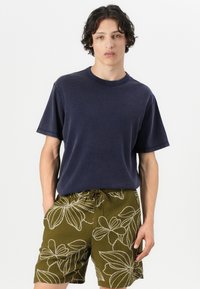 Navy blue crew-neck t-shirt paired with olive green shorts featuring white floral embroidery and an elastic drawstring waistband.