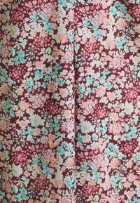 Tissu en coton fleuri de couleur bordeaux, présentant des fleurs roses et aqua avec des feuilles vertes, créant un imprimé vif et complet.