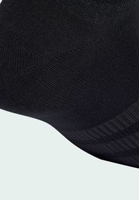 Crna čarapa s teksturiranim, rebrastim dizajnom i glatkom završnom obradom. Očitava se suptilni uzorak i fleksibilan materijal.