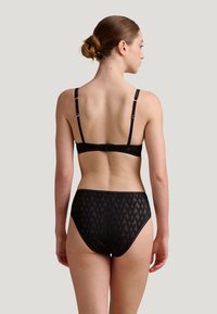 Zwart kanten lingerie-set met een gepatternde beha met verstelbare bandjes en een bijpassende high-waisted slip met een geometrisch ontwerp.