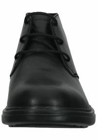 Chaussure en cuir noir avec une texture lisse, bout rond et six œillets pour les lacets. Présente un branding subtil sur le côté et une semelle durable.