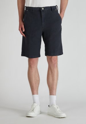 Navyblauwe katoenen korte broek met een relaxte pasvorm, voorkezen, riemlussen en een opgerolde zoom, gecombineerd met witte sneakers en kousen van crewlengte.