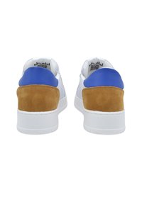 Zapatillas blancas con un talón de gamuza azul y beige, que presentan una parte superior de cuero suave, una suela blanca gruesa y un diseño minimalista.