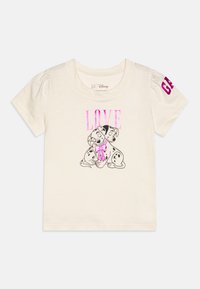 Camiseta de color crema con una textura ligera y suave. Presenta el texto "LOVE" en rosa y un gráfico de dos perros manchados, acentuado con un lazo.