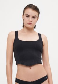 Musthave musta lühike top, mis on valmistatud elastneest kangast, millel on ruudukujuline kaelus, laiad rihmad ja vertikaalne õmblusdetail.