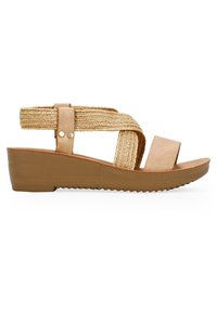 Sandalia de cuña con una tira texturada y tejida en dorado, acentos de cuero en color marrón claro y una suela de goma marrón con un patrón estriado para mayor agarre.