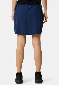 Navy blue skirt featuring a smooth texture, knee-length design, and an elastic waistband. Worn with black athletic shoes.