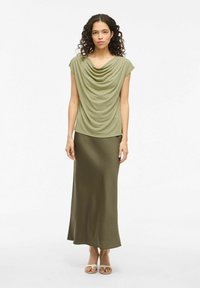 Top drapeado verde oliva con mangas cortas y una falda larga ceñida y fluida en color a juego. Tejido texturizado con detalles de caída suave.