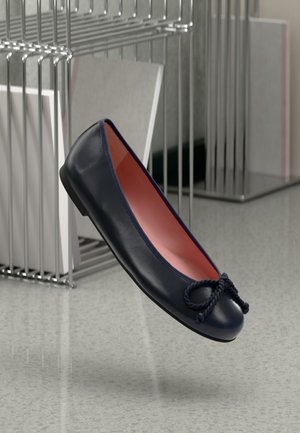 Bailarina de piel azul marino con puntera redondeada y detalle de lazo trenzado. Interior rosa y suela delgada de goma negra. Diseño minimalista.