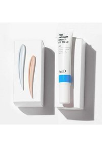 Tubo di crema per gli occhi con un design bianco e blu, accompagnato da due applicatori in azzurro chiaro e pesca su uno sfondo bianco.