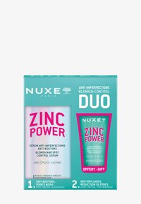 NUXE Zinc Power duo-förpackning har en glänsande silverserumflaska och en grön tubes. Båda har fet rosa text och tydliga hudvårdsbeskrivningar.