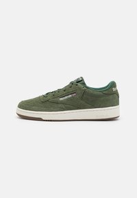 Baskets en daim vert avec semelle en caoutchouc blanche. Elles présentent des lacets plats, un col rembourré et un logo Reebok sur le côté et le talon.