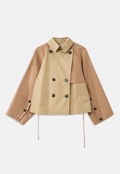 Kort, dobbeltbrystet jakke i lys tan og beige uldblanding. Har en krave, store sorte knapper og justerbar kant med snor.