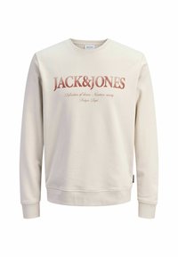 Sweat-shirt couleur crème avec col rond, poignets côtelés et un imprimé graphique à l'avant portant "JACK&JONES" en caractères gras et usés.