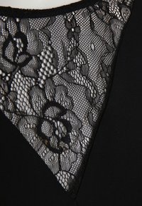Vestido preto com decote em V, apresentando uma intrincada inserção de renda na gola, destacando padrões florais contra um tecido sólido.