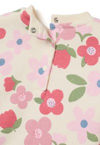 Top giallo chiaro con motivo floreale, decorato con fiori rosa e rossi, foglie verdi e chiusure a scatto sul collo. Realizzato in morbido cotone.