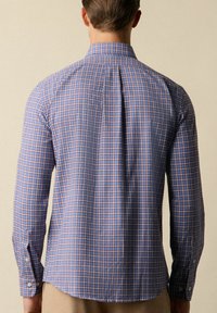 Camicia a maniche lunghe in plaid blu e rosa, con colletto a bottoni, piega sul retro e polsini con un bottone. Materiale in cotone.