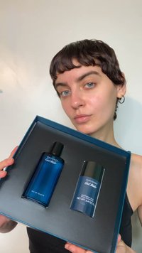 Zestaw Davidoff Cool Water zawierający niebieską szklaną butelkę wody toaletowej oraz pasujący niebieski dezodorant w sztyfcie, umieszczone w czarnym pudełku z niebieską pokrywką.