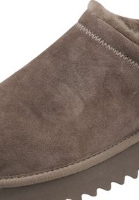 Brune suedés slip-on sko med avrundet tå og teksturert finish. Har kontrasterende sømmer og en tykk, rippet gummisåle.