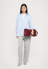 Lyseblå skjorte med knap, grå vide bukser og bordeaux ruskinds taske. Sorte og hvide sandaler fuldender outfittet.