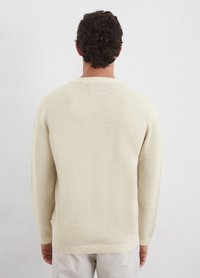 Pullover sweater in light beige, ribbed crew neck, long sleeves, soft texture, straight hem, minimal branding tag at the side.