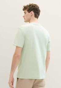 Mintgrön t-shirt med kort ärm och rund halsringning, med en slät textur och avslappnad passform. Inga synliga mönster eller detaljer.