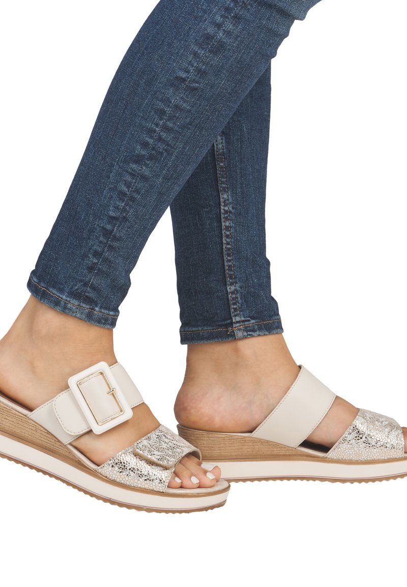 Sandales compensées beiges avec une sangle métallique texturée, une bande supérieure lisse et une semelle en bois. Design à bout ouvert avec une boucle réglable.