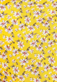 Gul tyg med ett blommönster med vita och rosa blommor, omgiven av gröna blad, vilket skapar en livlig, strukturerad design.