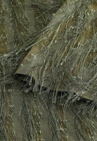 Kudokset, joissa on oliivivihreä pohja metallikoristeilla ja pitkillä, fringed kuituilla, luoden kerroksellisen ja dynaamisen ilmeen.