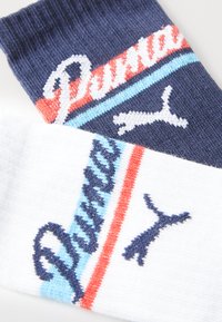 Δύο ζευγάρια κάλτσες: ένα ναυτικό μπλε με λευκές, κόκκινες και ανοιχτό μπλε ρίγες και λογότυπο; ένα λευκό με ναυτικές ρίγες και λογότυπο. Πλέκτο υλικό.