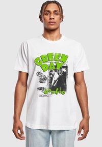 Hvid bomulds T-shirt med et iøjnefaldende grønt "GREEN DAY" logo og sort-hvide grafikker. Casual pasform med rund halsudskæring og korte ærmer.