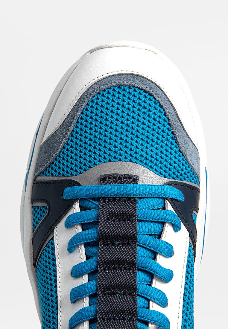 Blauer Mesh-Sportschuh mit einer weißen Lederzehenkappe und grauen Wildlederakzenten. Auffällige marineblaue Schnürsenkel und strukturierte Stoffdetails.