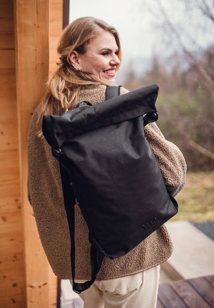 Černý batoh s rolovacím uzávěrem a nastavitelnými popruhy, vyrobený z odolné tkaniny. Hladký povrch, minimalistický design, bez viditelných log.