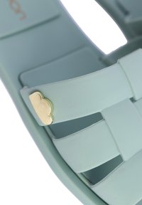 Sandalia de goma de color azul claro con tiras trenzadas y un acento dorado con forma de nube. Textura suave y diseño abierto para una mejor transpirabilidad.