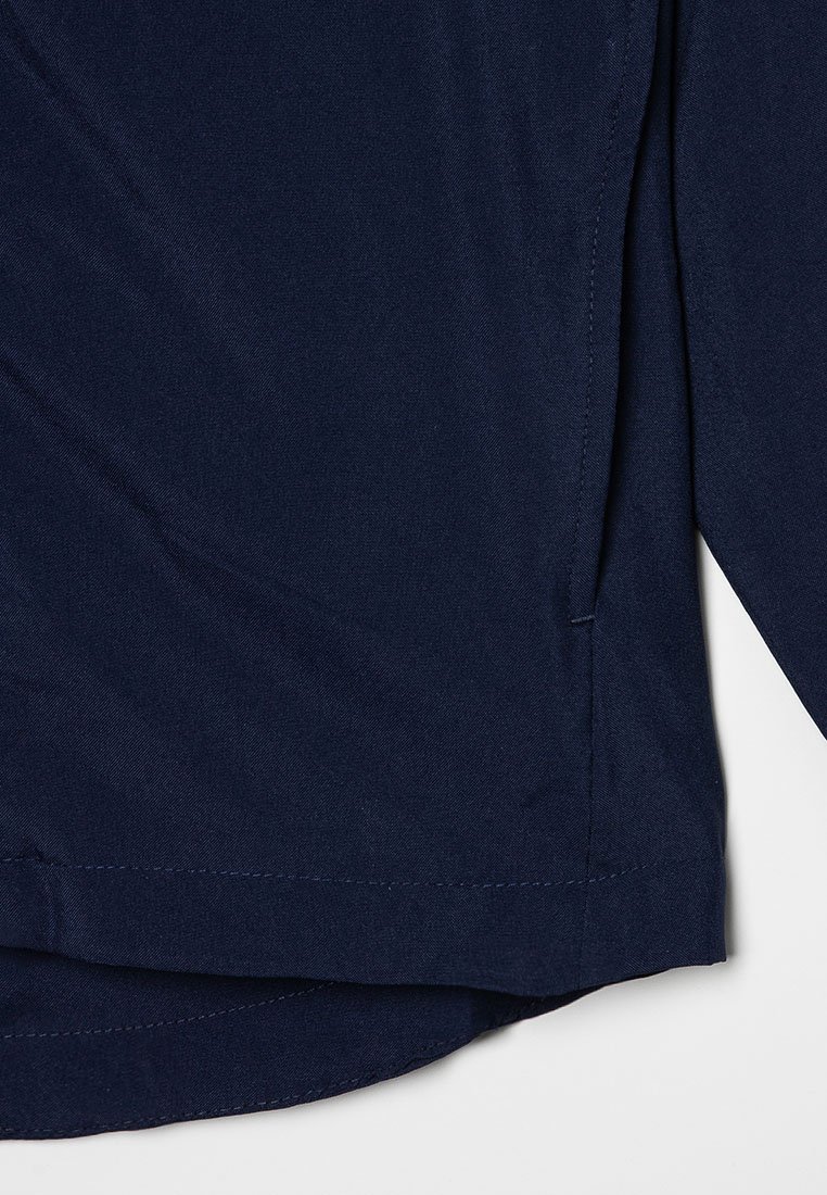 Navyblauwe shirt van gladde stof met een rechte zoom en zijsplitten. Kenmerkt zich door contrasterende stiksels langs de randen.