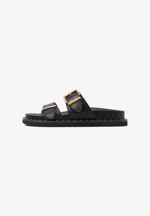 Zwarte leren slideslippers met twee banden met gouden gespen, een vlakke rubberen zool en contrasterende stiksels rond de basis.