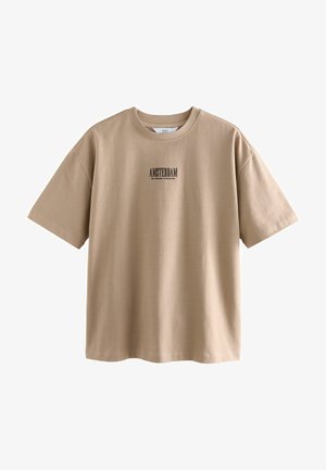 Beige Baumwoll-T-Shirt mit kurzen Ärmeln, das einen schwarzen Druck mit "AMSTERDAM" auf der Brust hat. Lockere Passform und glatte Textur.