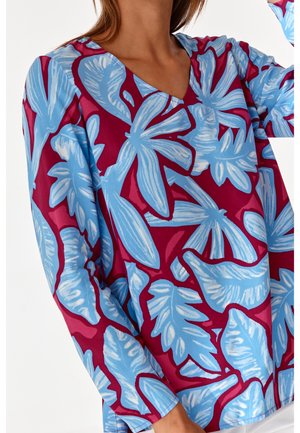 Haut à manches courtes avec un fond maroon vif et de grands motifs de feuilles tropicales bleues, design en V et coupe décontractée.