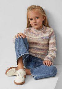 Mehrfarbiger, strukturierter Strickpullover mit Rundhalsausschnitt, kombiniert mit knöchellangen, hellblauen Jeans und weißen Sneakers mit braunen Akzenten.