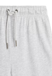 Jasnoszare dresy z elastycznym pasem w talii, regulowanym sznurkiem i metalowymi końcówkami. Miękka tekstura z subtelnym melanżowym wzorem.