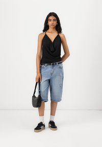 Must mustata top, millel on drapert front, helesinine kulunud teksashorts Bermuda, must perforatsiooniga käekot ja mustad tossud valgete triipudega.