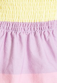 Šaty s nařasením se třemi horizontálními barevnými bloky: pastelově žlutá, levandulová a světle růžová. Materiál je měkký s texturovaným povrchem.
