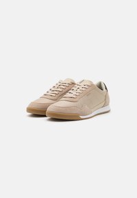 Brune og beige sneakers i semsket og tekstilmateriale, med rund tå, gummisåle, snøring og et minimalistisk design.