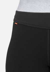 Leggings neri con una cintura larga, dotati di un'etichetta arancione, realizzati in un tessuto morbido e elasticizzato con una vestibilità aderente.