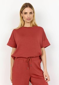 Rode katoenen t-shirt met korte mouwen, ontspannen pasvorm en een brede halslijn, gecombineerd met bijpassende jogpants met trekkoord. Eenvoudig, effen kleurontwerp.